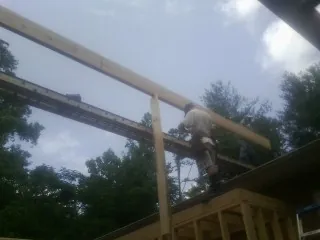 Carpenter setting a ridge beam over a new addition frame — Ice Dam Removal by Roofing Brothers in Gueydan