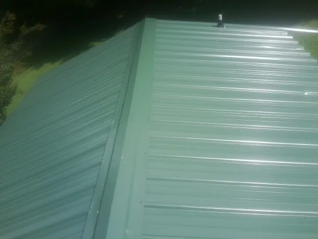 New green metal panels meeting at the ridge of a roof — Flat Roof Repair work by our crew in Gueydan