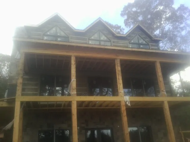 Dormers and porch framing on a large log home under construction — Roof Coating work by our crew in Gueydan