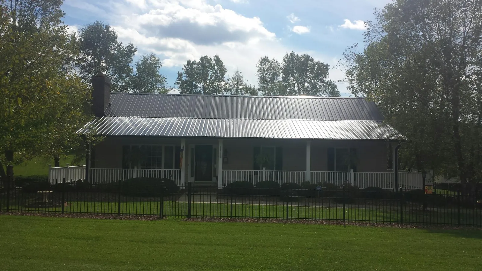 Gray metal roof on a brick ranch with a full width front porch — Gutter Guard Installation work by our crew in Gueydan