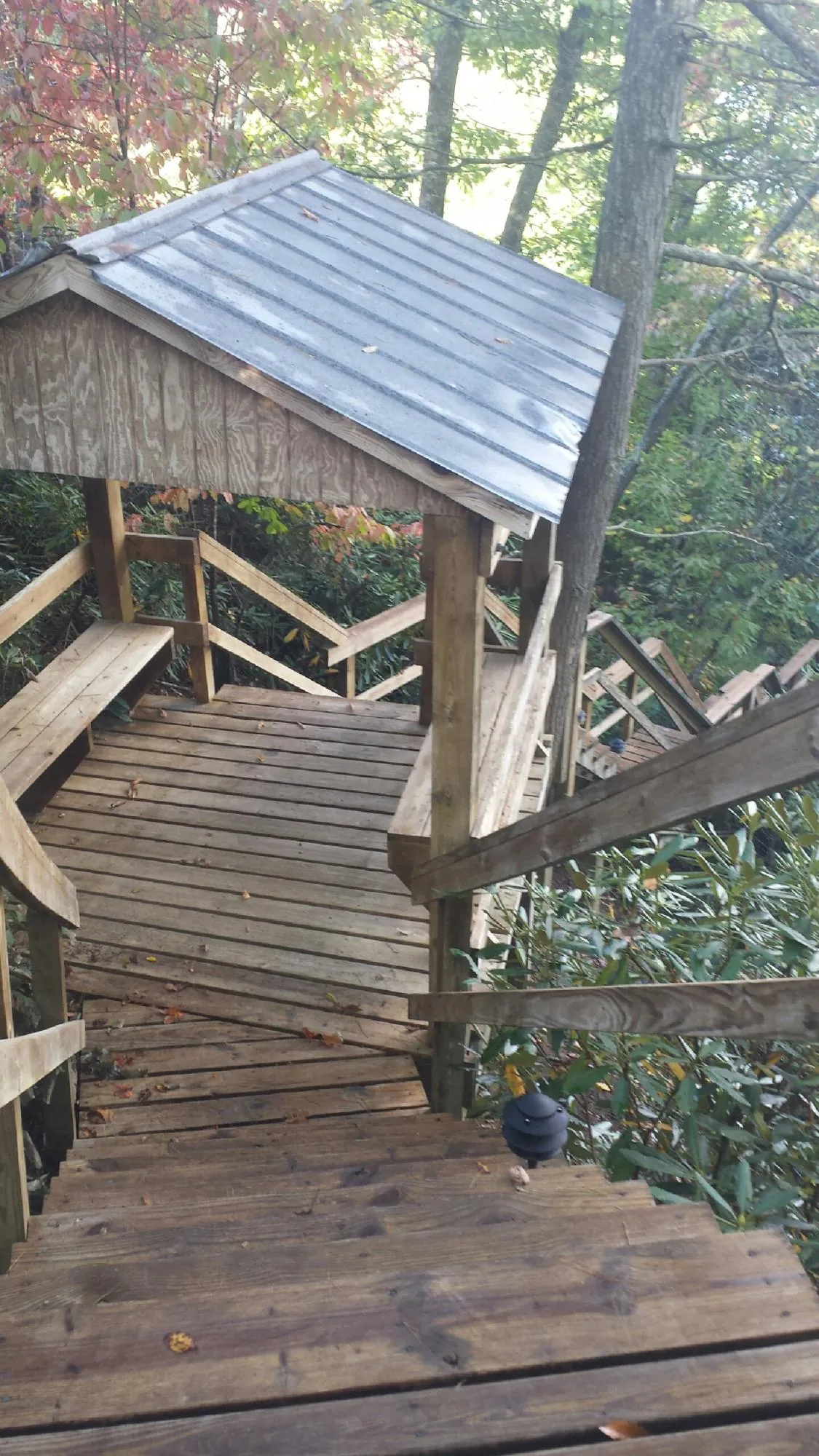 Metal roofed shelter over wooden steps on a wooded walkway — Skylight Repair & Installation work by our crew in Gueydan