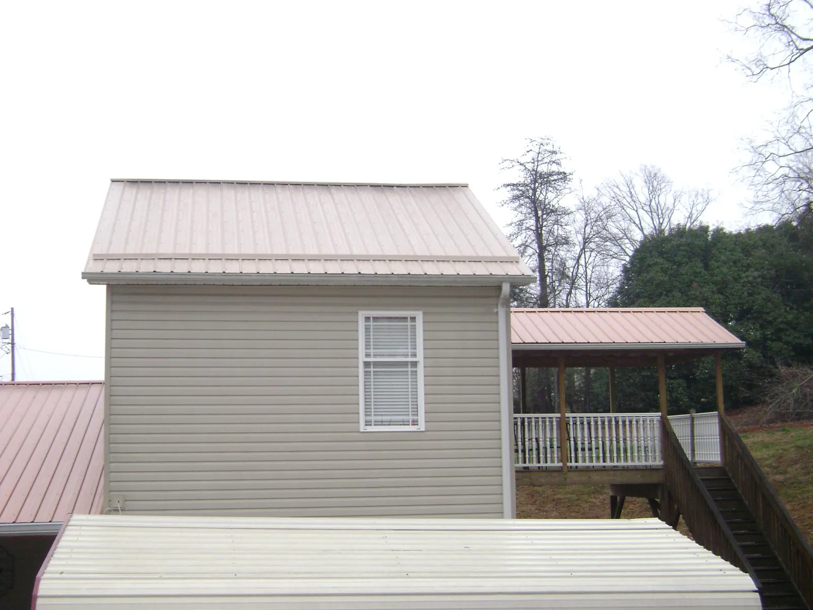 Tan metal roofs on a two story addition and attached porch, from a Roof Replacement job in Gueydan