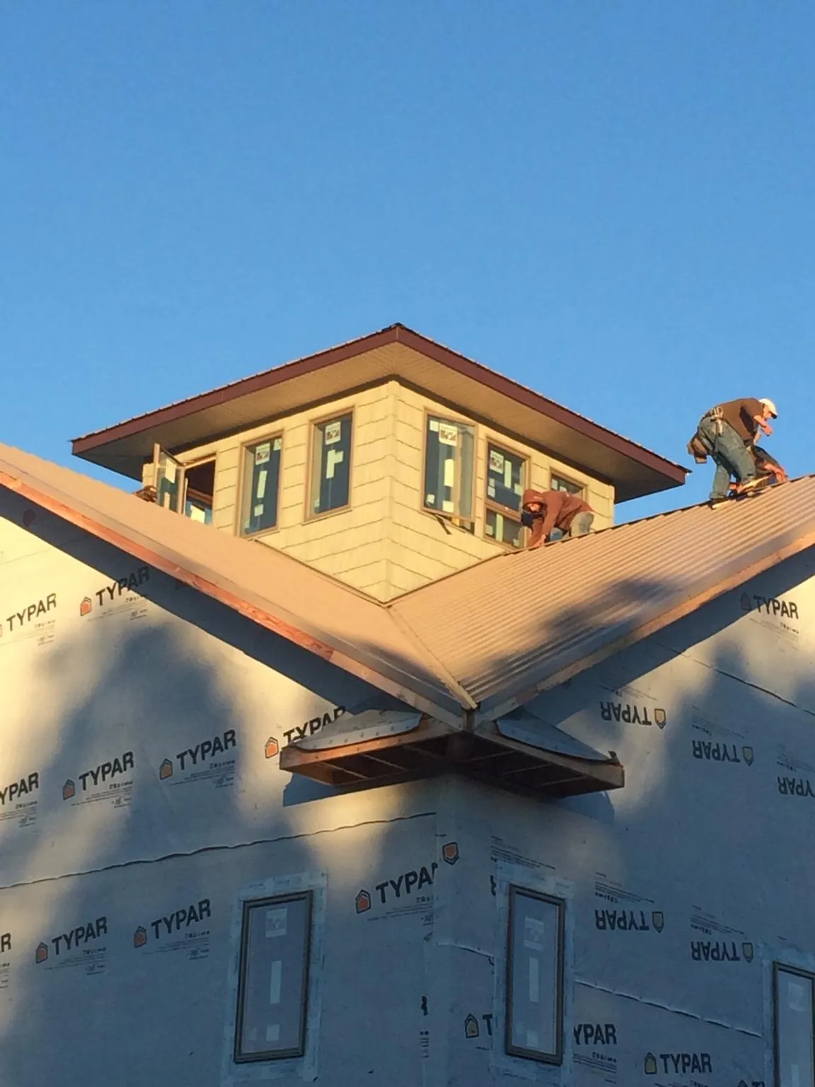 Roofers working around a rooftop cupola on a new metal roof at sunset — Roof Waterproofing in Gueydan by Roofing Brothers